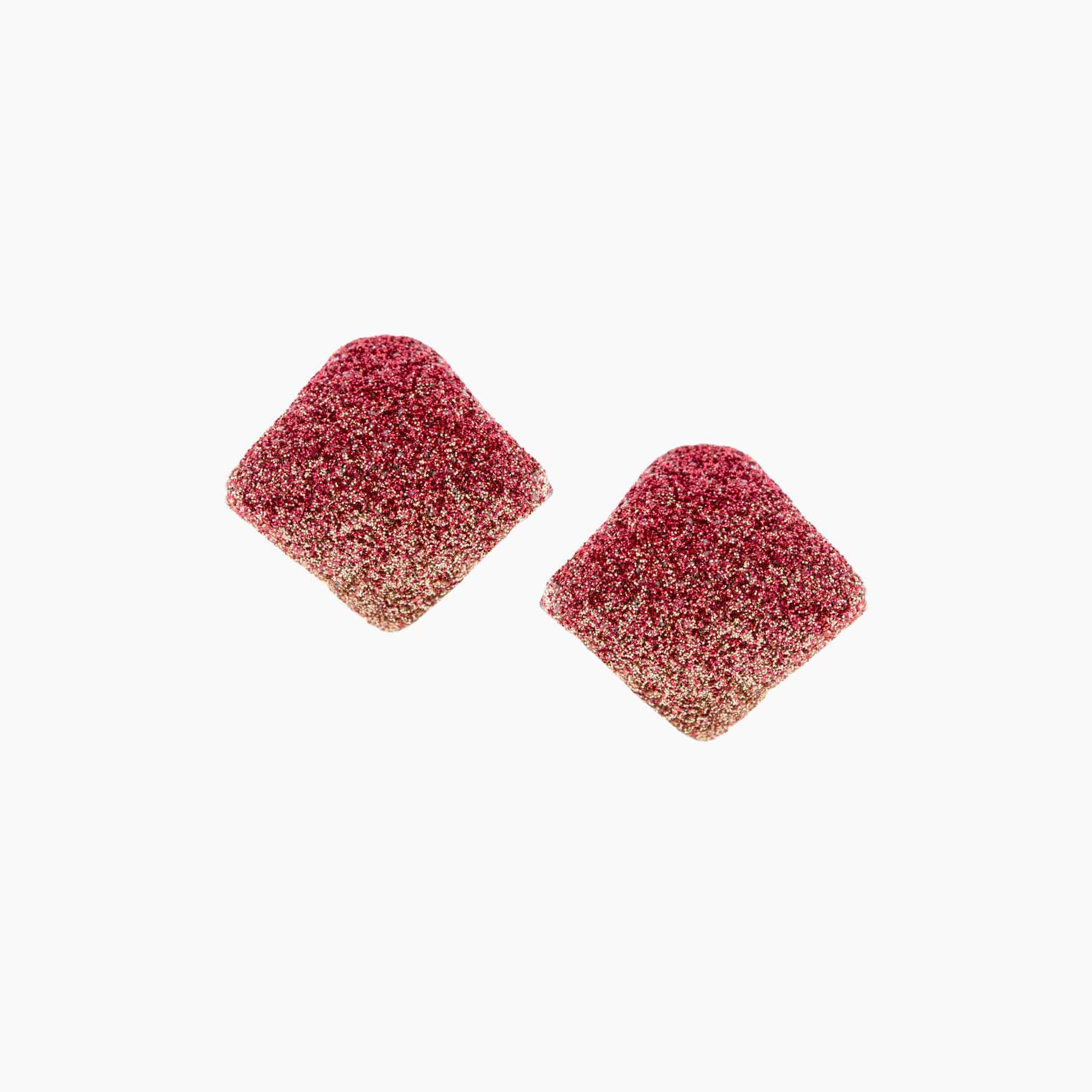 Two pinkish-red textured square earrings on a white background