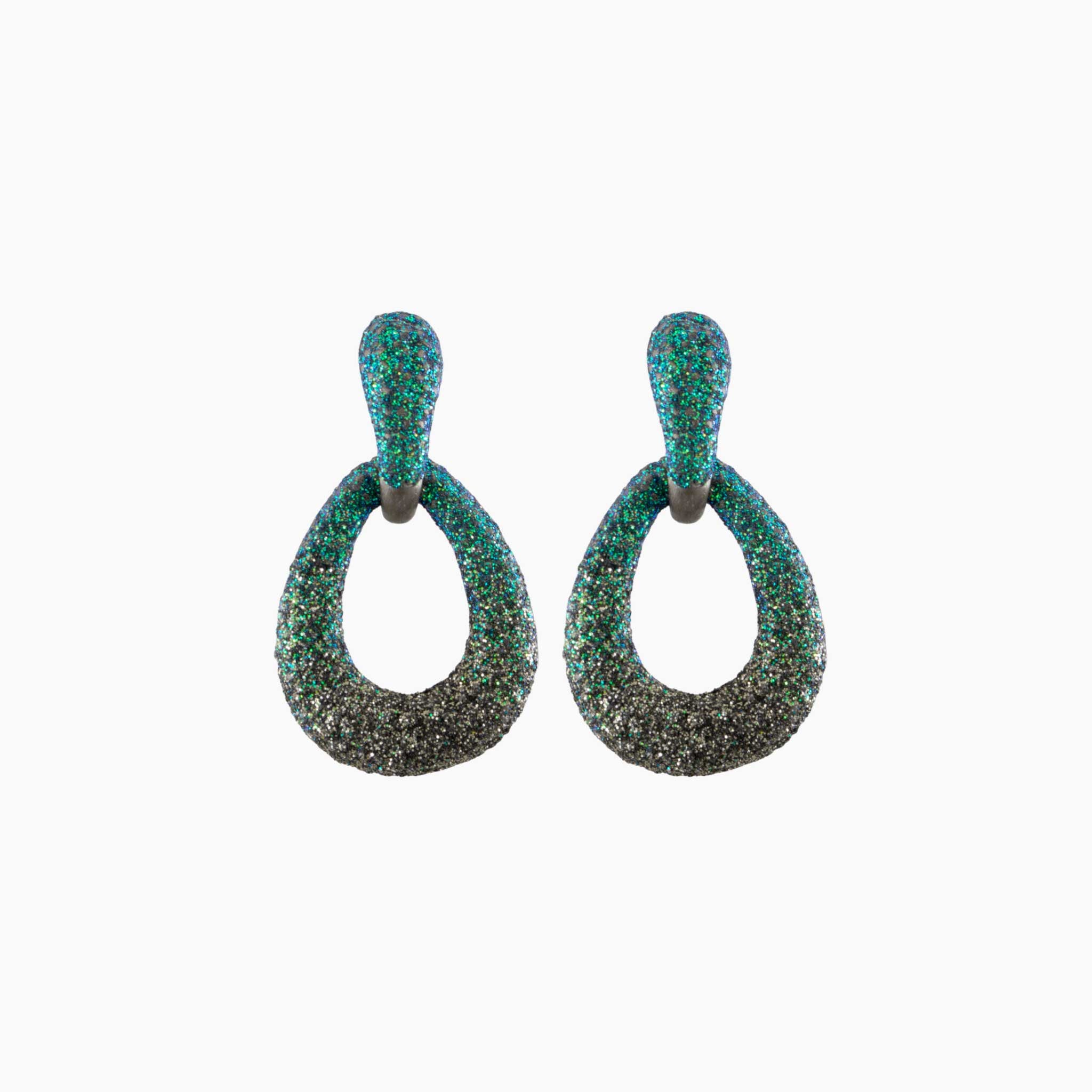 Pair of earrings with green and black glittery finish on a white background