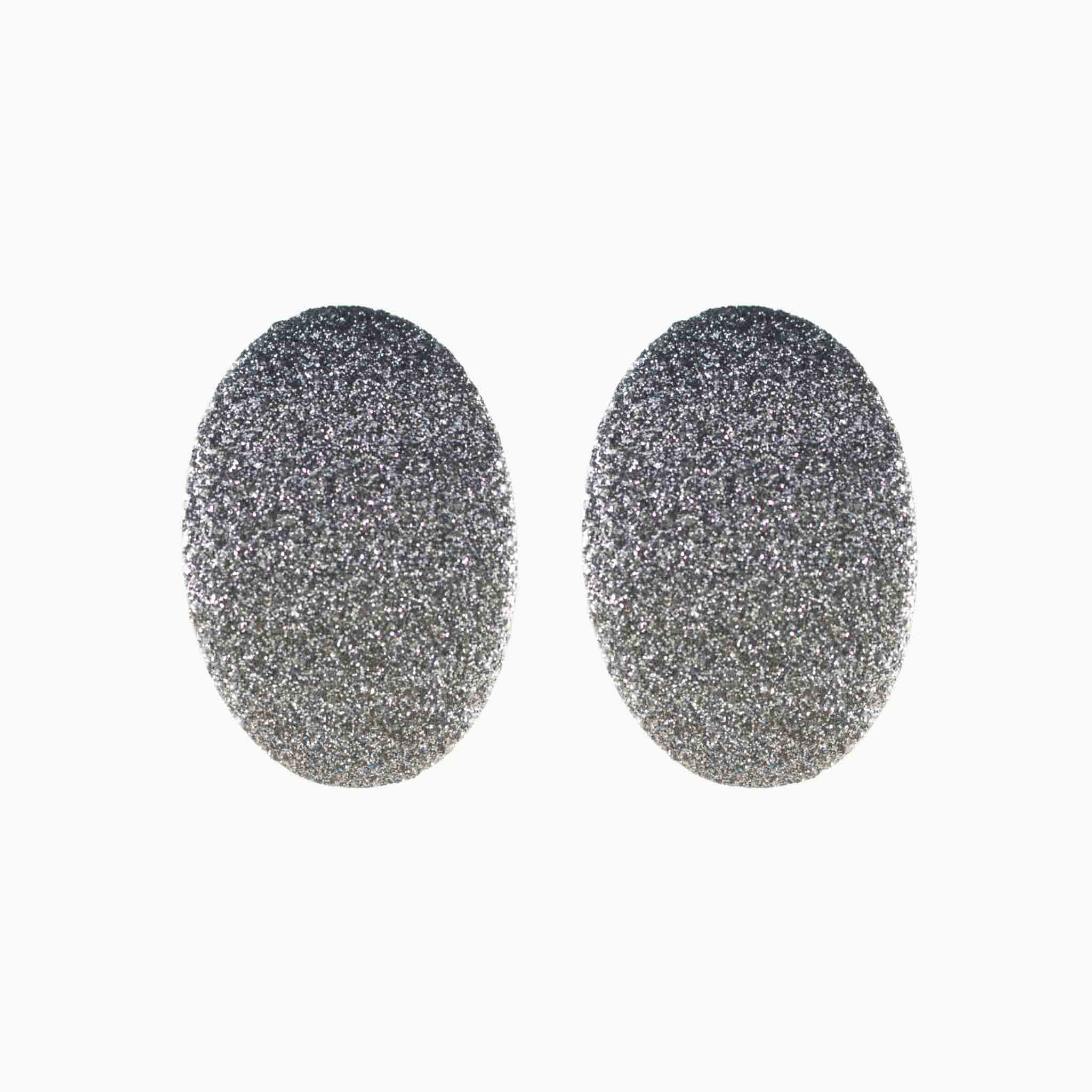 Pair of silver glittery oval earrings on a white background